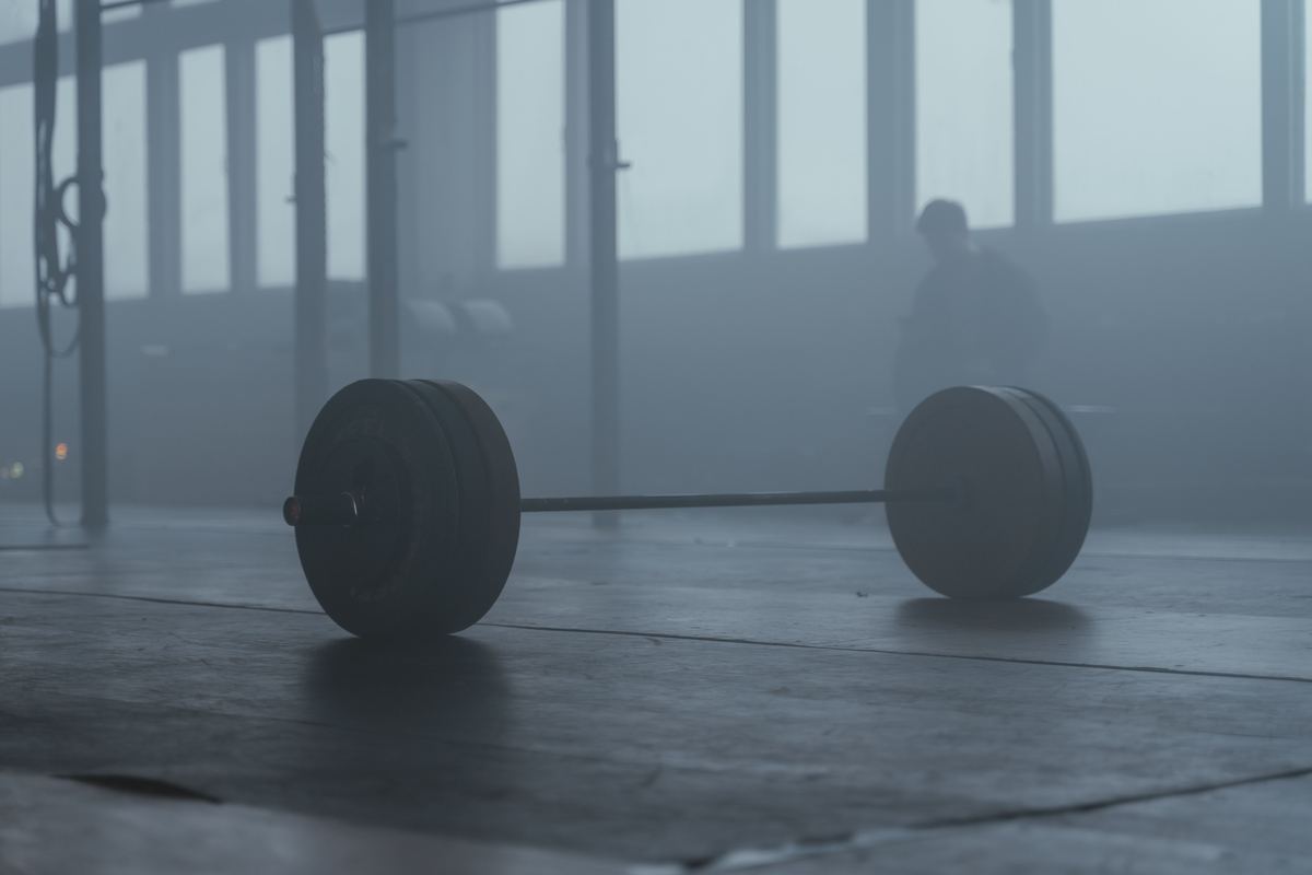 Een geladen barbell op de vloer van een gym, in een waas van licht.